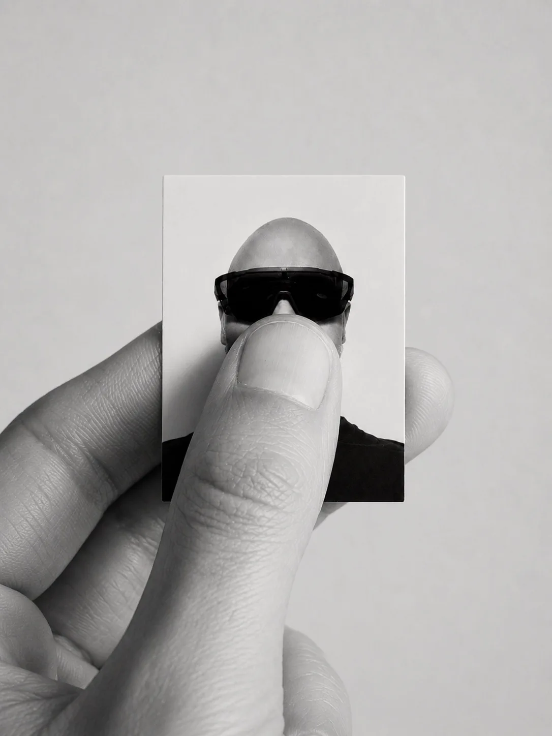 A hand holding a miniature monochrome portrait of the DigiHold founder.