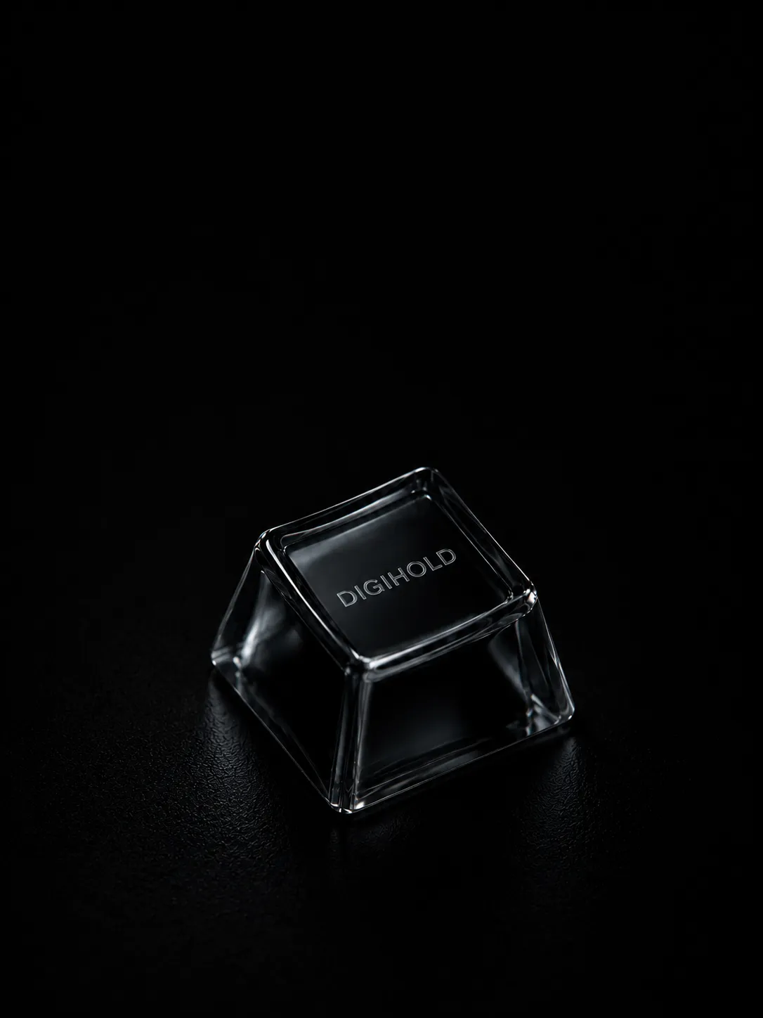A transparent black DigiHold keycap resting on a textured black surface.